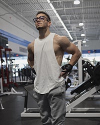 a man wearing glasses standing in a gym